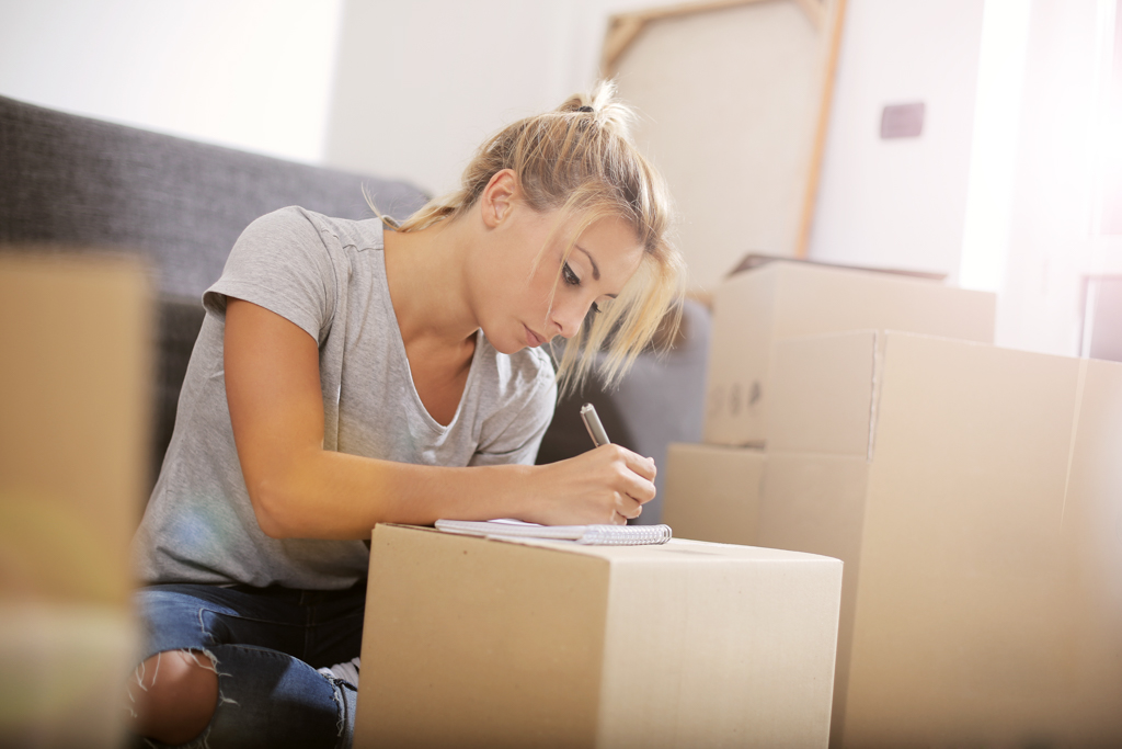 Girl writing on paper while using cardboard box as table