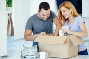 Lagerung nuetzliche Informationen - Mann und Frau packen glückliche eine Umzugskiste ein.