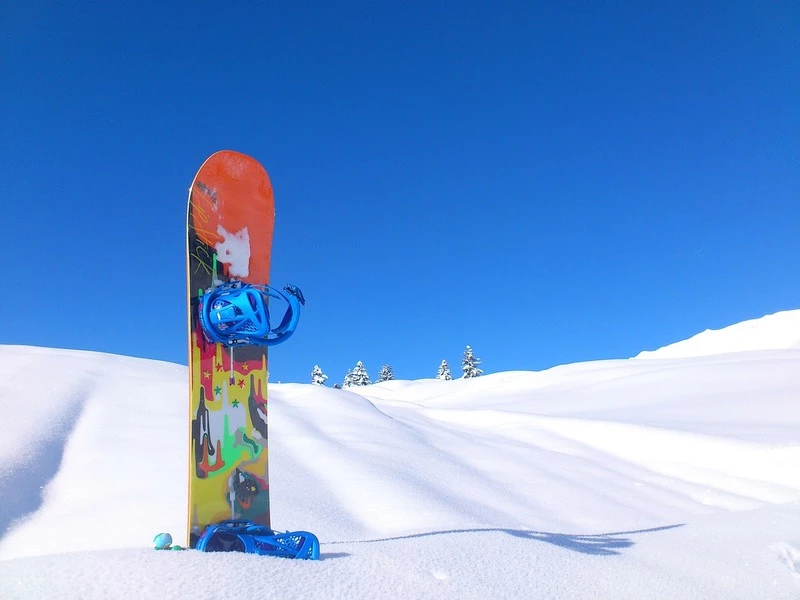 Snowboard stuck in the snow with a blue sky behind it