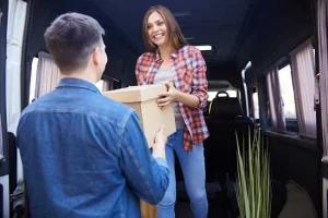 Woman hands a moving box over to a man
