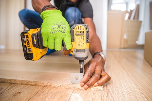 Renovating your house - man with green glove using a handheld drill